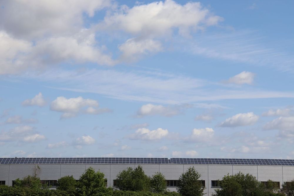 A large commercial building with a rooftop solar array in tilted rows on its flat roof — the load and residual-capacity question a specialist confirms before any panels go up